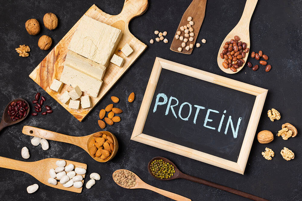 Слово &laquo;Protein&raquo; латиницею на дошці крейдою і різні продукти навколо, які багаті на білок.