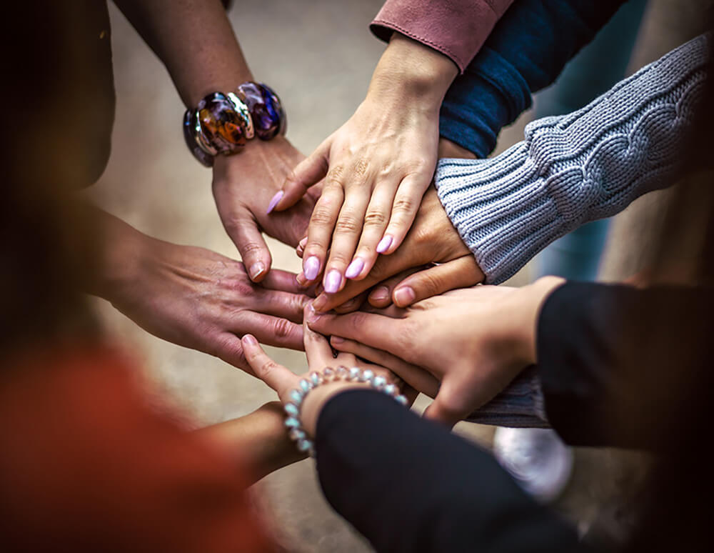 Кисти мужских и женских рук в общем кругу, который символизирует командную работу или дружбу