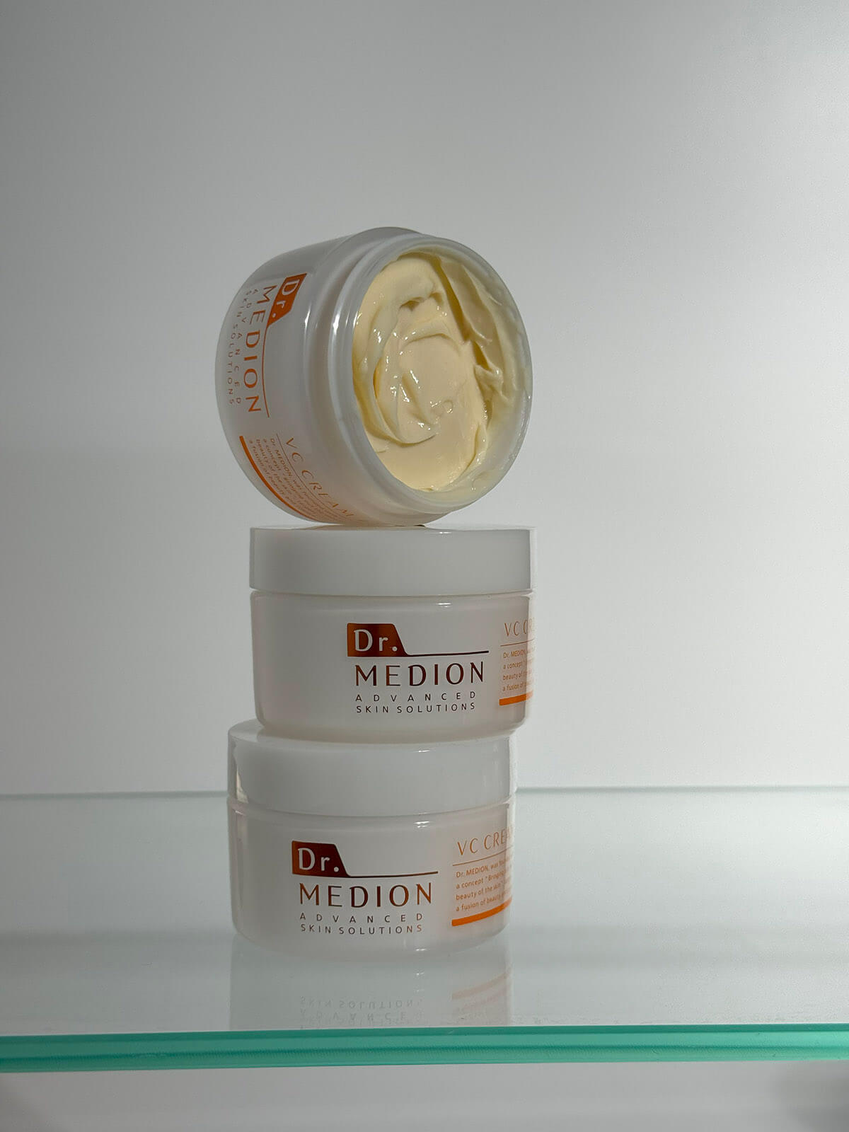 Три банки крему Dr. MEDION VC Cream + вертикально одна на іншій. Верхня банка з відкритою кришкою, що дозволяє добре розглянути колір і текстуру крему