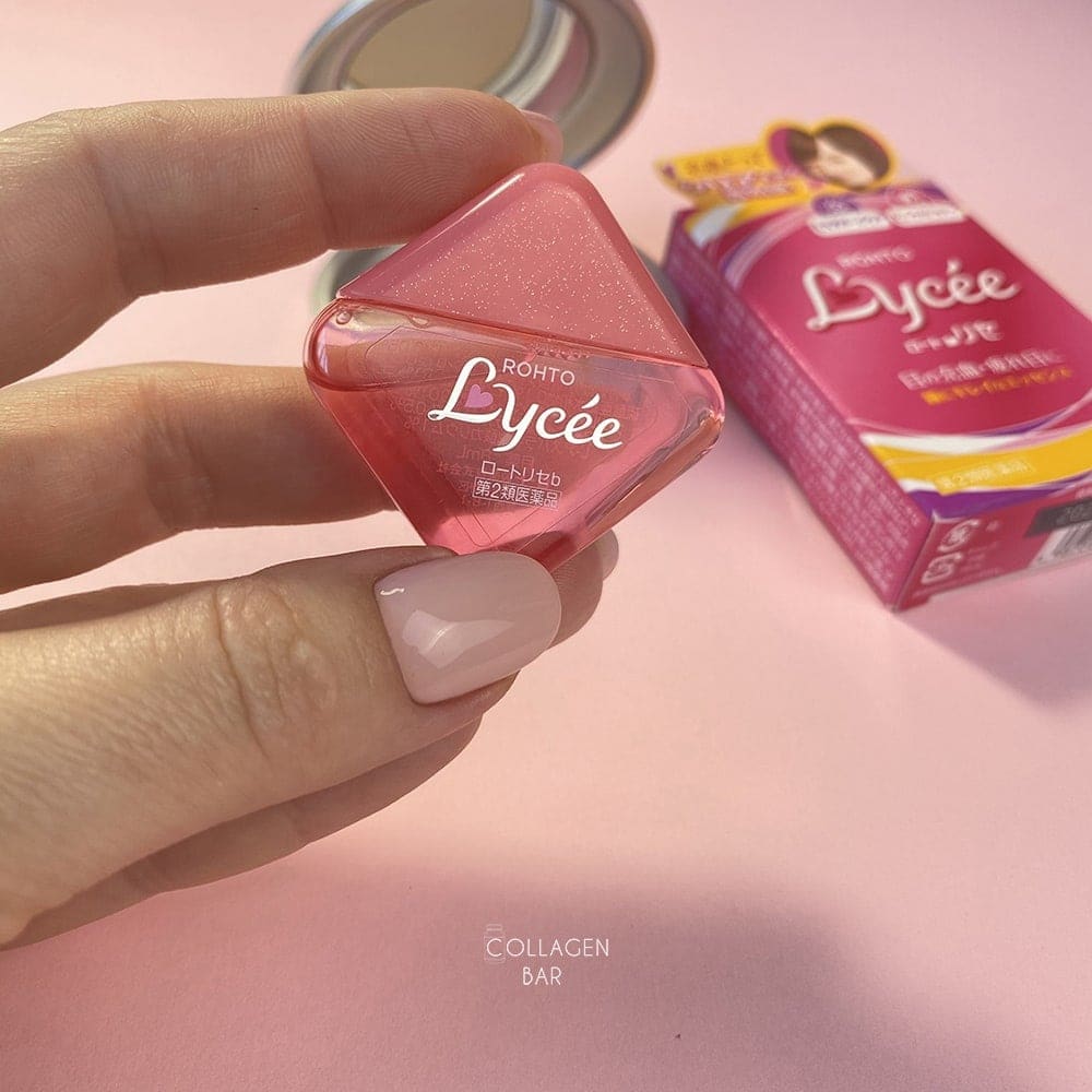Капли Rhoto Lycee без упаковки в женской руке на фоне картонной упаковки