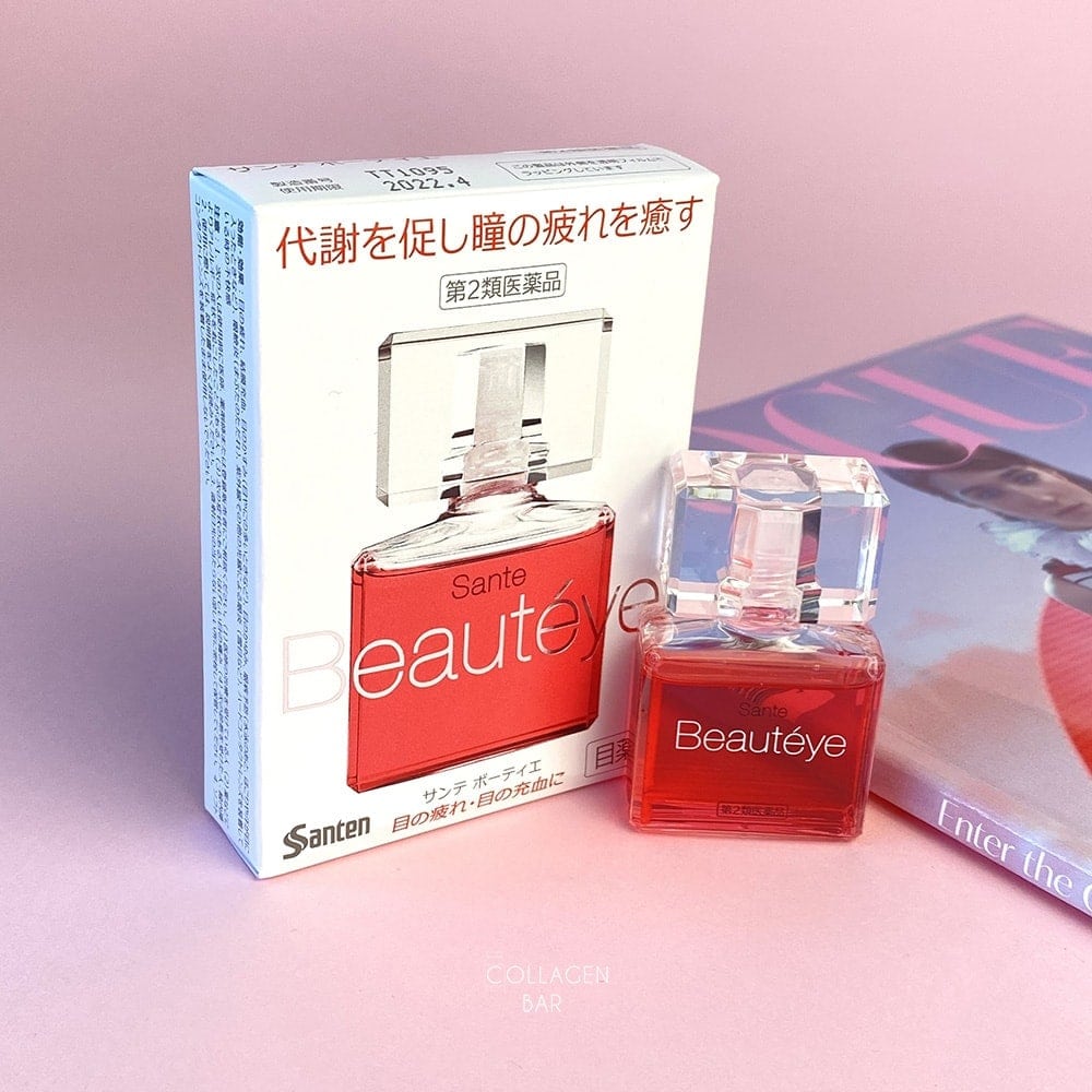 Капли для глаз Sante Beauteye на розовом фоне рядом с глянцевым журналом