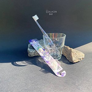 Іонна зубна щітка APAGARD 'Crystal' Toothbrush у прозорій скляній склянці з камінням на чорному тлі