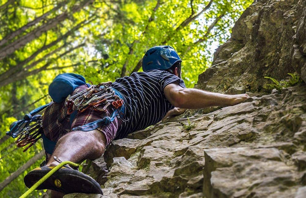 Людина з альпіністським спорядженням піднімається по скелі вгору