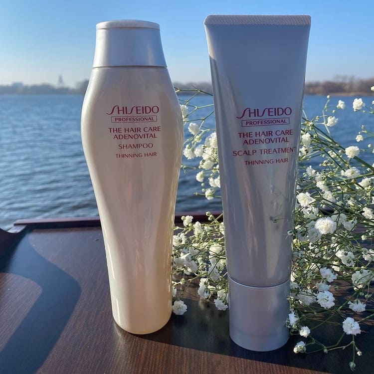 Шампунь і бальзам для шкіри голови SHISEIDO ADENOVITAL на тлі водойми з білими дрібними польовими квітами
