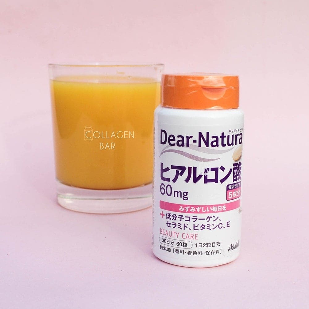 Гіалуронова кислота Dear-Natura від концерну Asahi та склянка апельсинового соку на рожевому тлі.