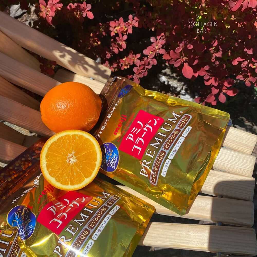 Две упаковки коллагена Meiji Amino Premium NEW с апельсинами на деревнном шезлонге