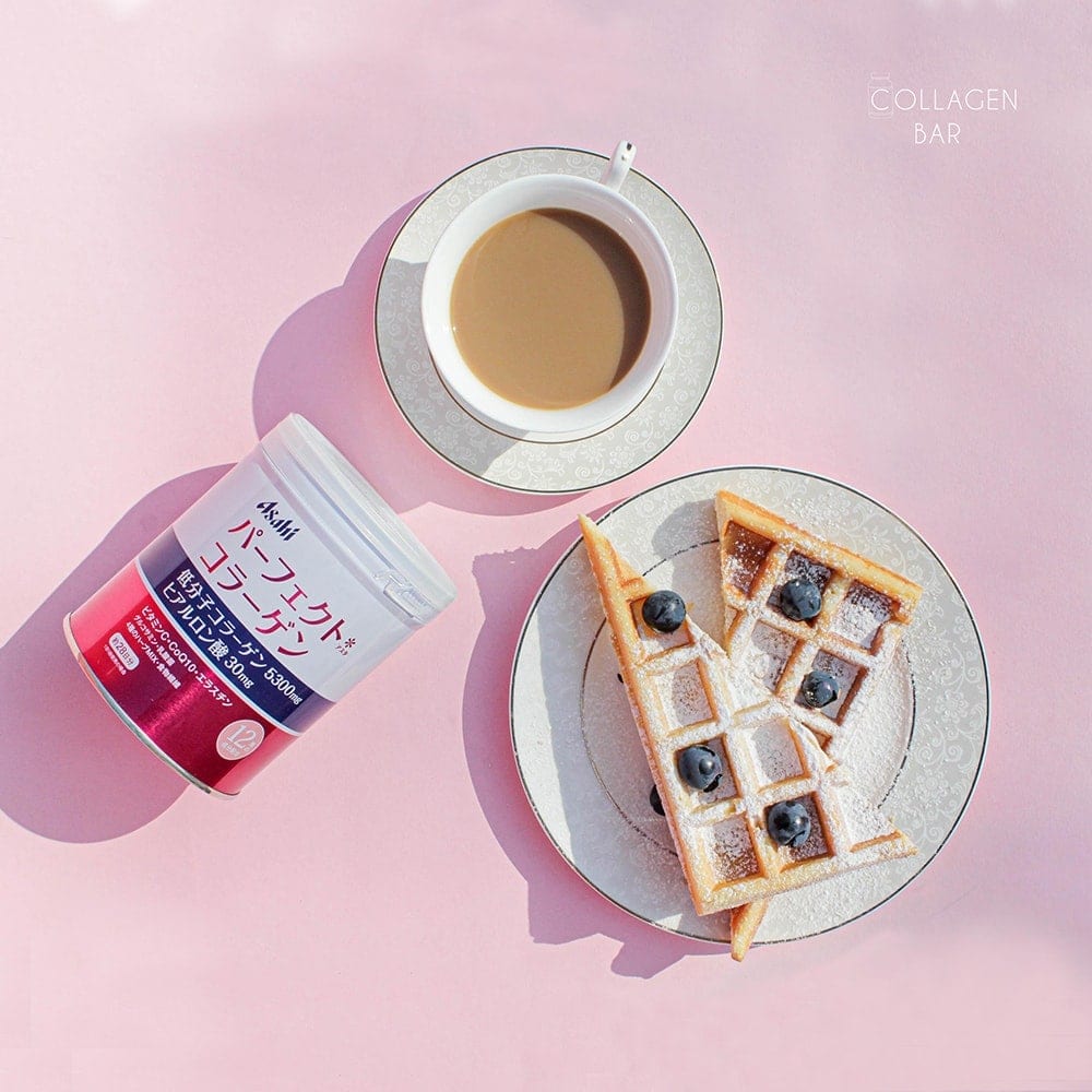 Колаген Asahi Asta Perfect Collagen у банці з чашкою кави і тортом на рожевому тлі. Вид зверху.