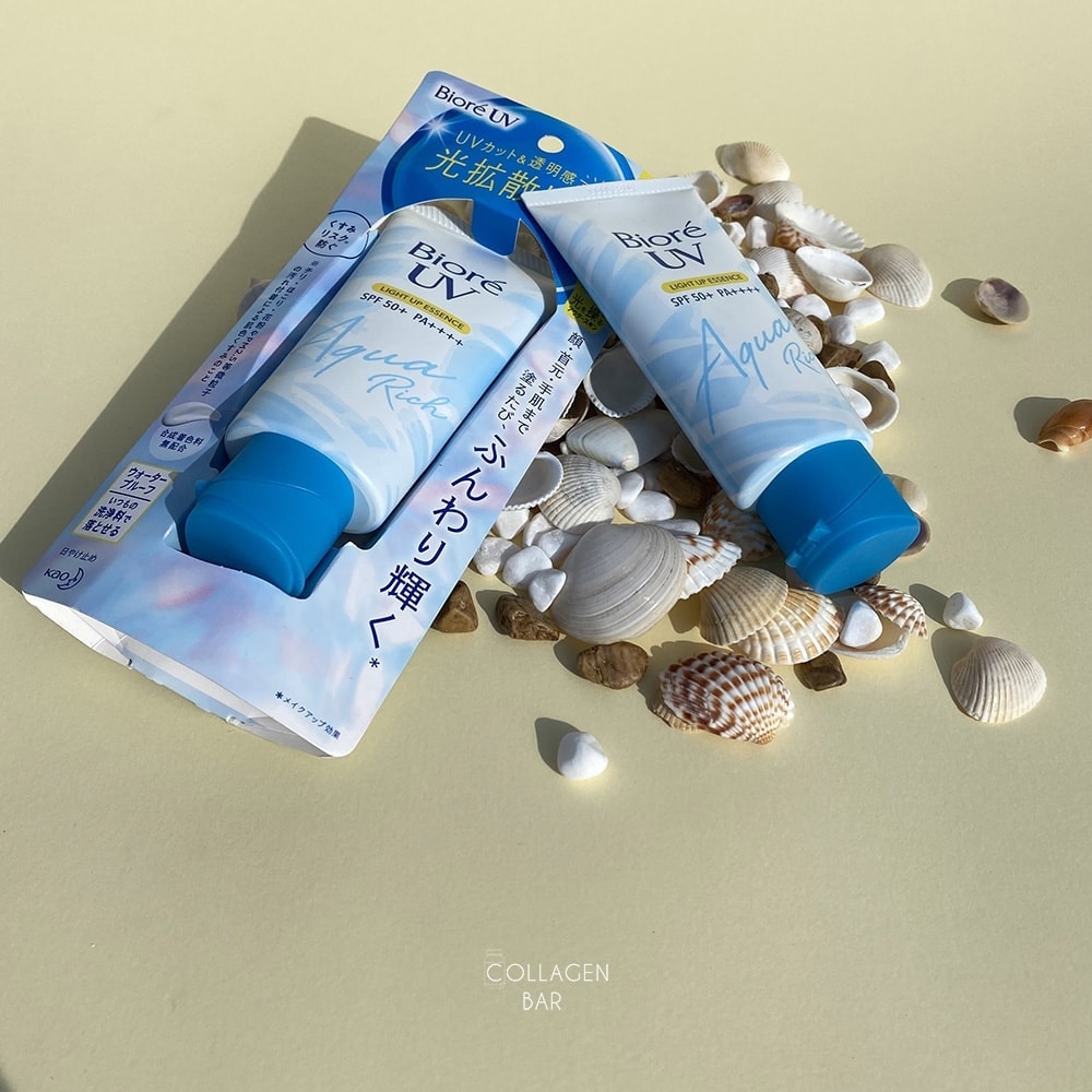 Два санскріни Biore UV Light UP Essence з морськими мушлями на світло-жовтому тлі