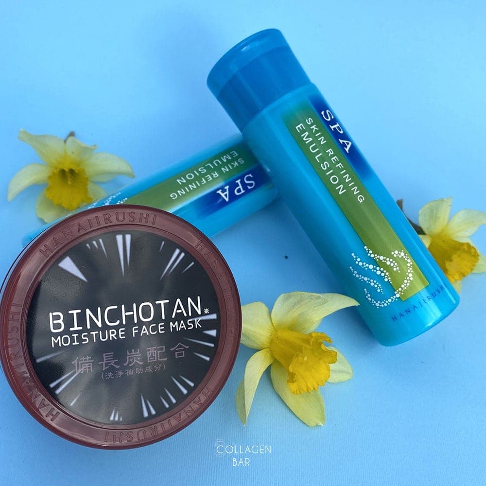 Эмульсия Hanajirushi SPA Skin Refining Emulsion и очищающая маска Hanajirushi Binchotan Face Mask на голубом фоне с цветами нарцисса