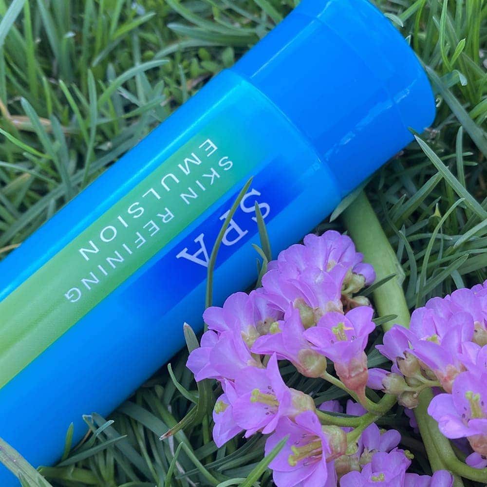 Эмульсия Hanajirushi SPA Skin Refining Emulsion в зеленой траве с цветками бадана