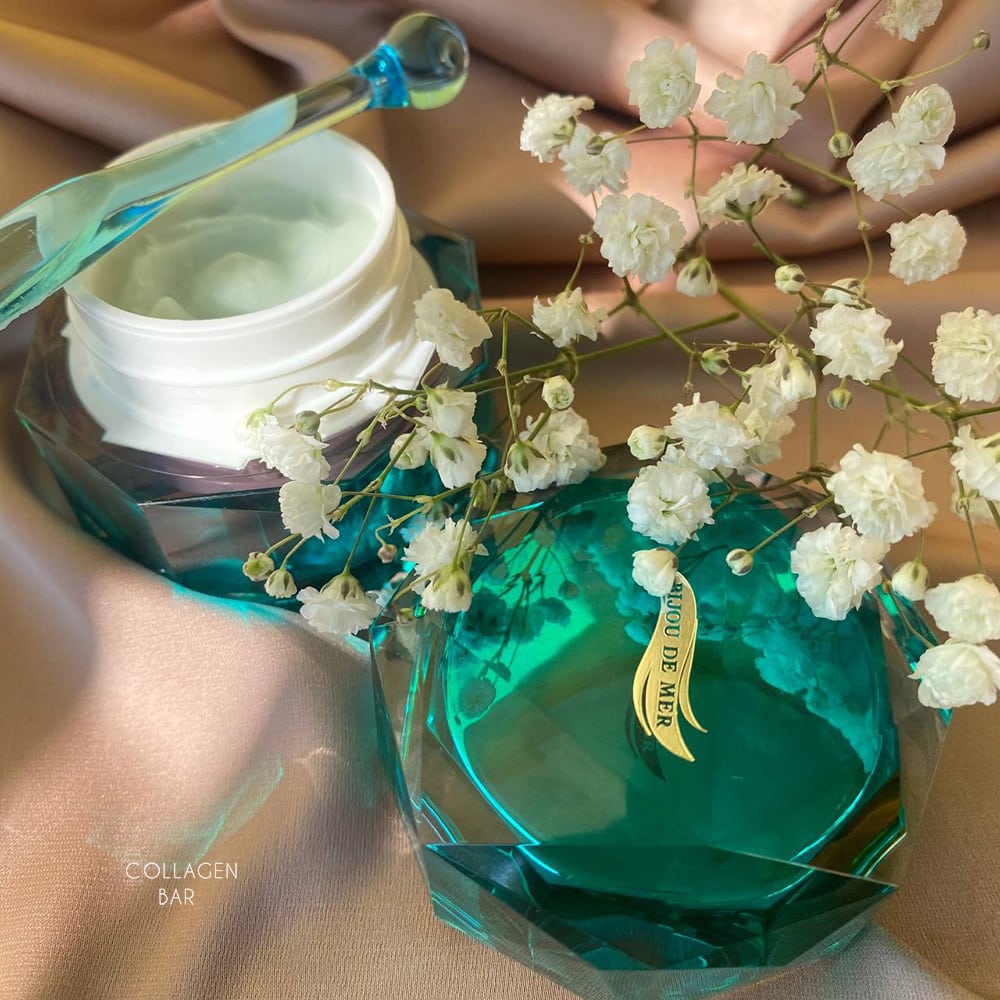 Відкрита банка ревіталізаційного крему для обличчя BIJOU DE MER Rejuve face Renewal Cream зі спатулою і гілкою білих квітів