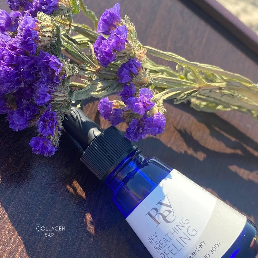 Делікатний кислотний пілінг REY Breathing Peeling з фіолетовими польовими квітами на коричневій дерев'яній поверхні