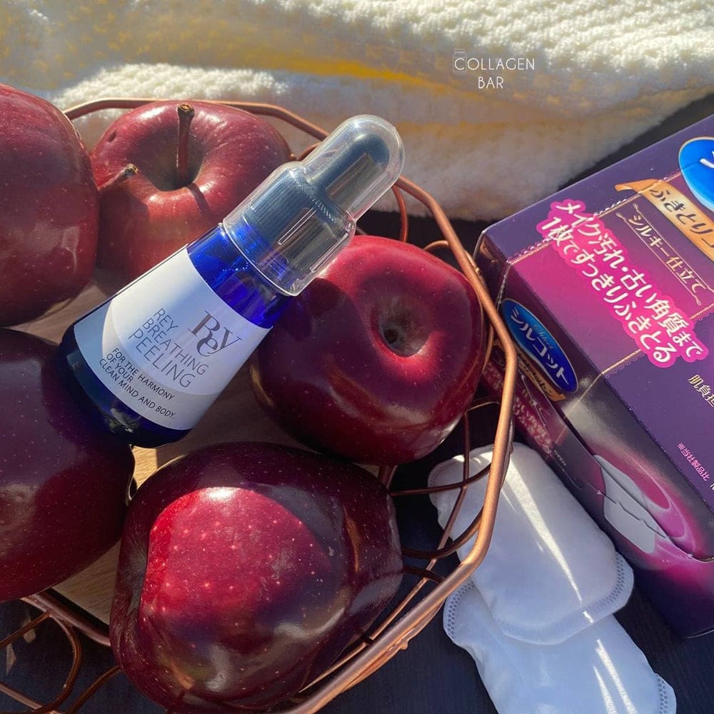 Делікатний кислотний пілінг REY Breathing Peeling у кошику з червоними яблуками і фрагмент упаковки з пафами UNICHARM Silcot Wiping Cotton