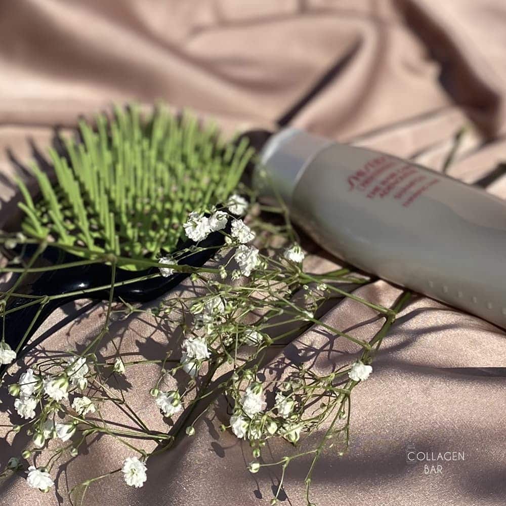 Шампунь SHISEIDO ADENOVITAL на светло-коричневой ткане с зеленой расчсекой и веточкой с маленькими белыми цветками