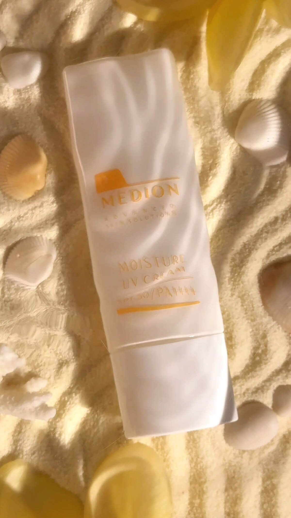 UV-крем Dr. Medion SPF 50 під водою на піску з морськими мушлями. По воді біжить брижі.