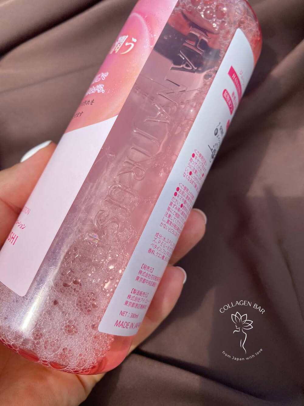 Лосьон HANAJIRUSHI Juicy Cleansing Lotion в женской руке, повернутый тыльной стороной. На бутылке нанесен логотип HANAJIRUSHI