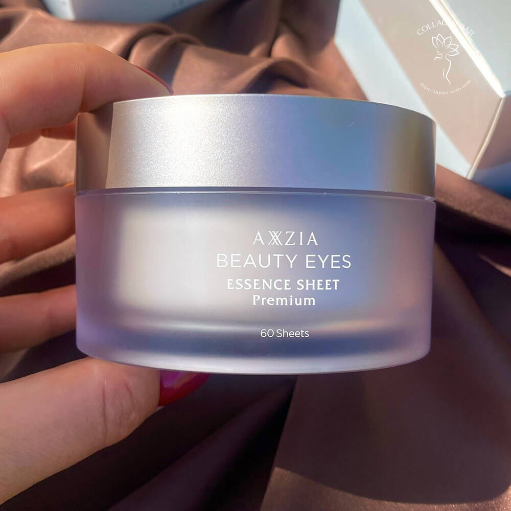 Патчи AXXZIA BEAUTY EYES Essence Sheet Premium в женской руке с красным маникюром