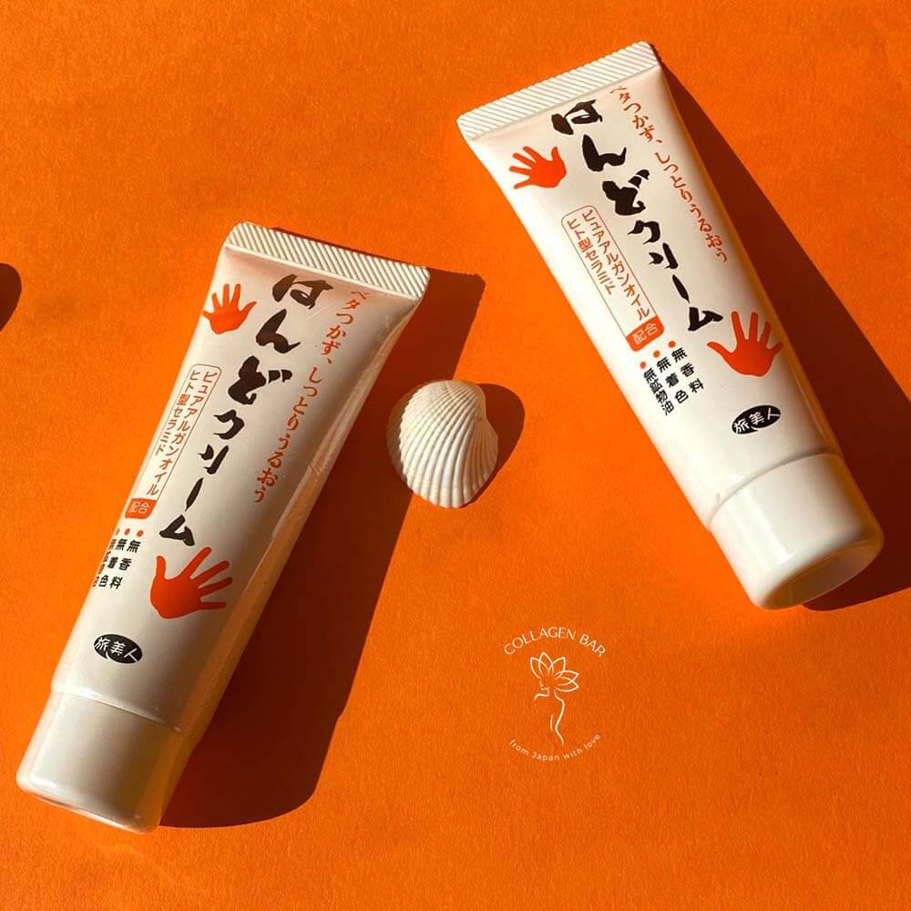 Два тюбики крему для рук Azuma Tabibijin Hand Cream на помаранчевому тлі з маленькими морськими мушлями 