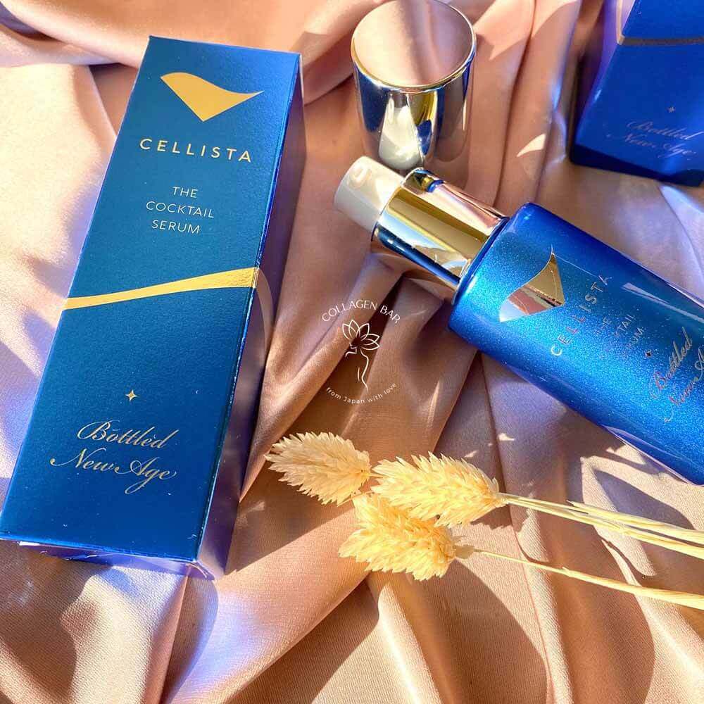 Дві коробки і флакон сироватки CELLISTA The Coctail Serum з відкритим ковпачком на коричневій тканині з колосками