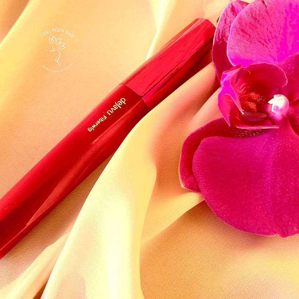 Туш Dejavu Fiberwig Ultra Long Mascara без упаковки на коричневій тканині з квіткою фіолетової орхідеї