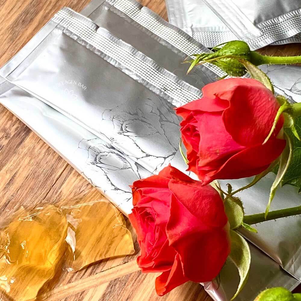 Несколько стиков GINZA TOMATO Chieco Rose Placenta Jewel и свежие красные розы рядом. Кусочки желе, извлеченные из стика. Хорошо видна консистенция и цвет желе.