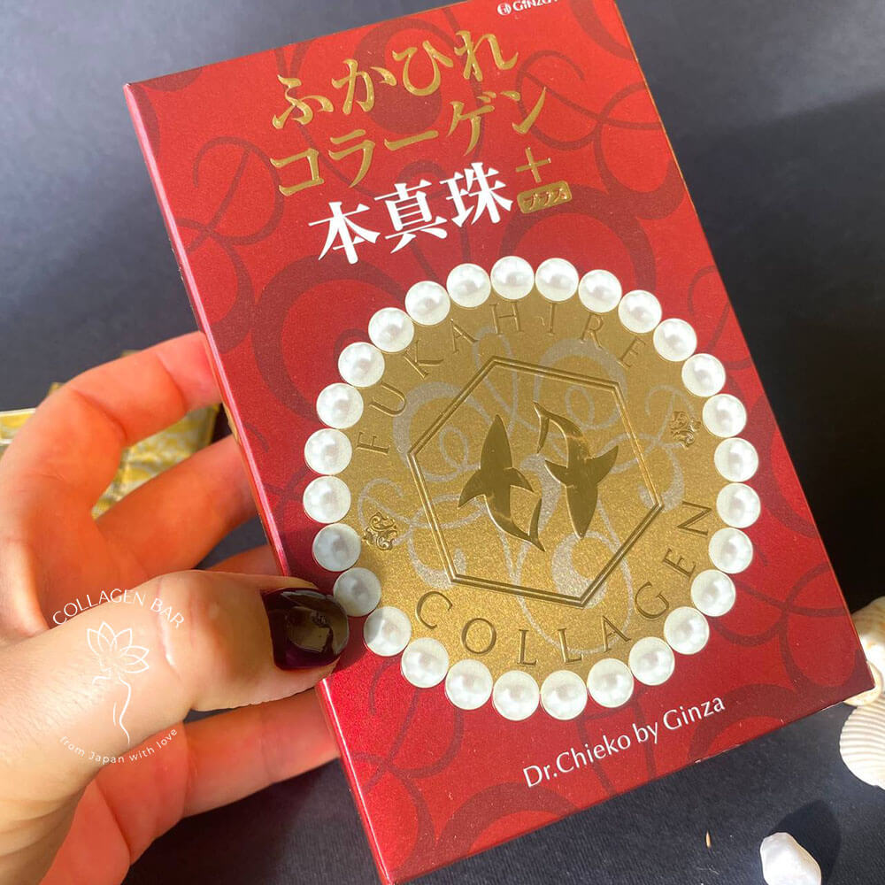 Коробка з колагеном GINZA TOMATO Shark Fin Collagen Pearl PLUS у жіночій руці з бордовим манікюром