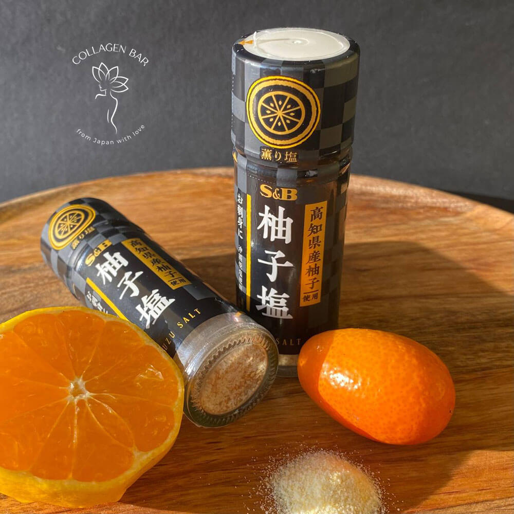 Дві баночки окинавської морської солі S&B Kaori Yuzu Salt з половинкою мандарина на дерев'яній тарілці