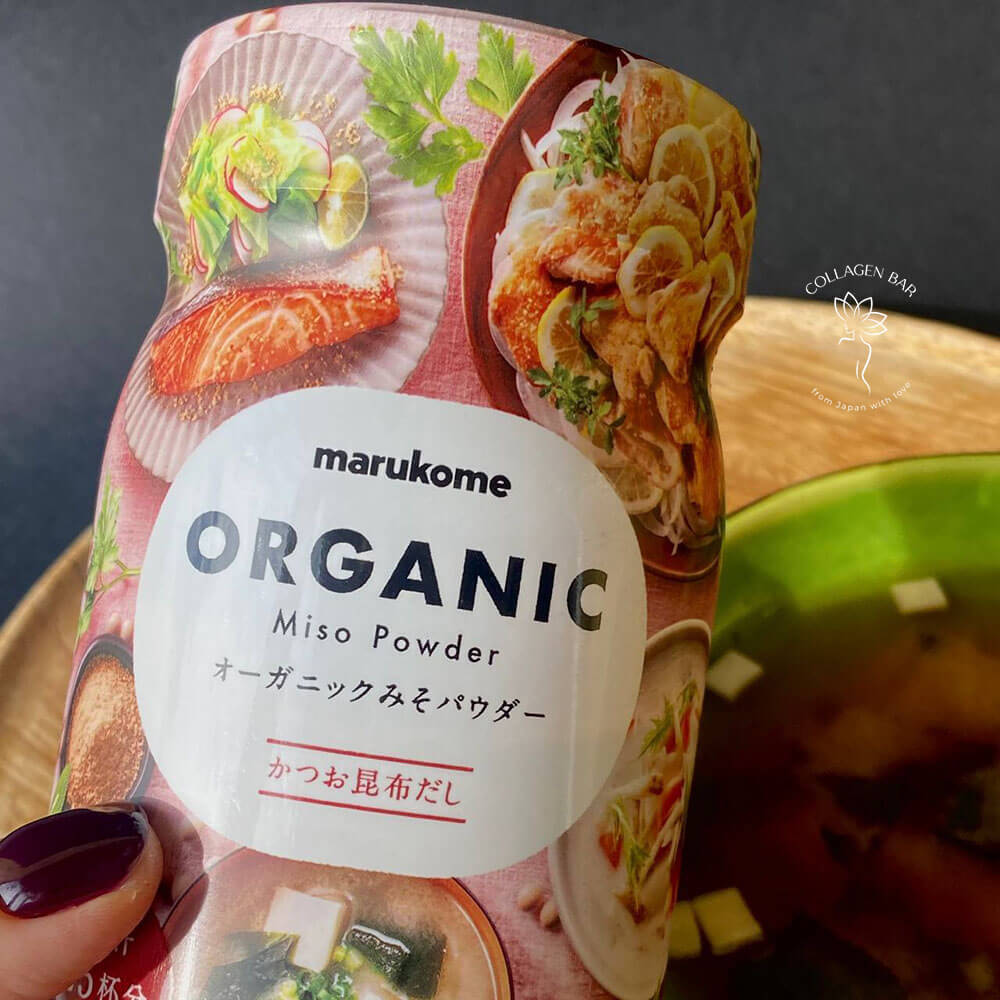 Сублімоване місо з бульйоном дасі MARUKOME Organic Miso Powder у жіночій руці з бордовим манікюром