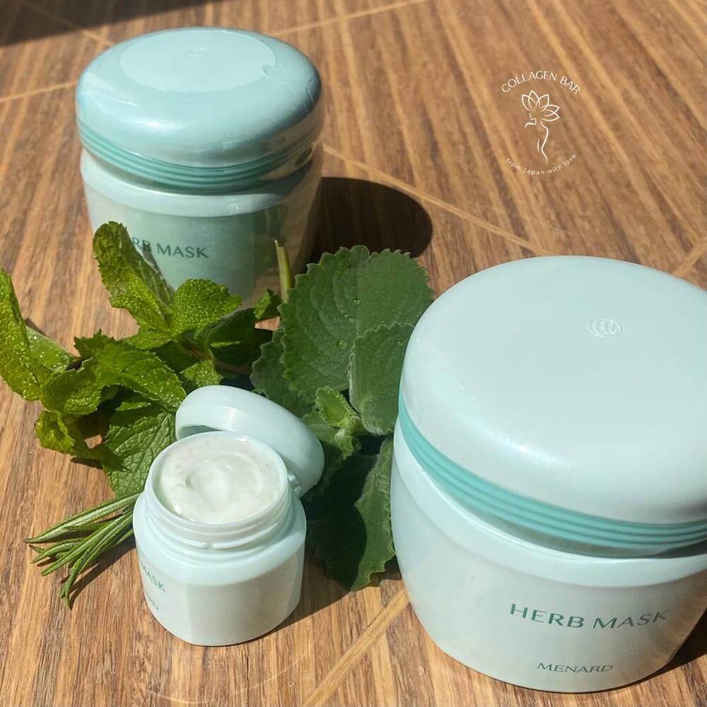 Велика банка маски MENARD Herb Mask на 120 грам і travel-мініатюра об'ємом 20 грам на дерев'яному столі з листям меліси