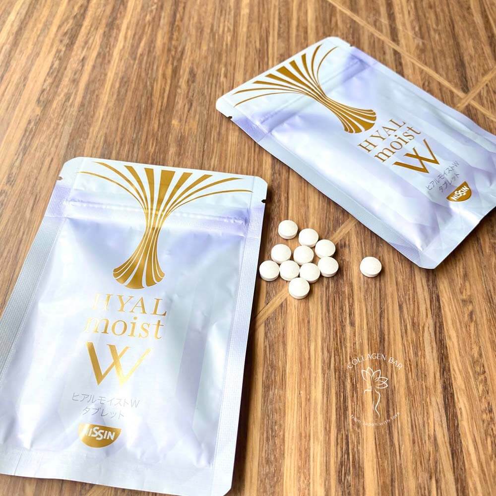 Дві упаковки NISSIN HYAL MOIST W Tablet і таблетки поруч на дерев'яній поверхні з красивим візерунком