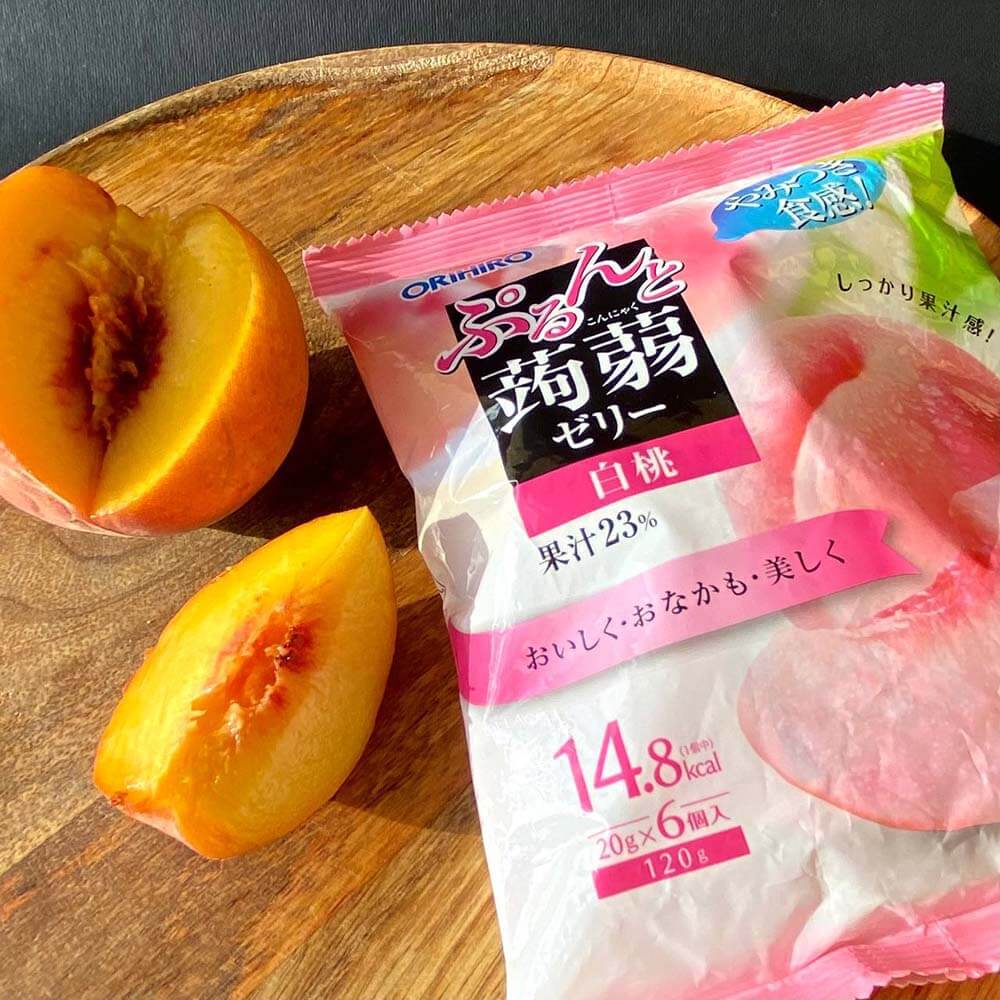 Уппаковка конфет ORIHIRO Purunto Konnyaku Jelly Pouch White Peach на круглом деревянном блюде с кусочками персика