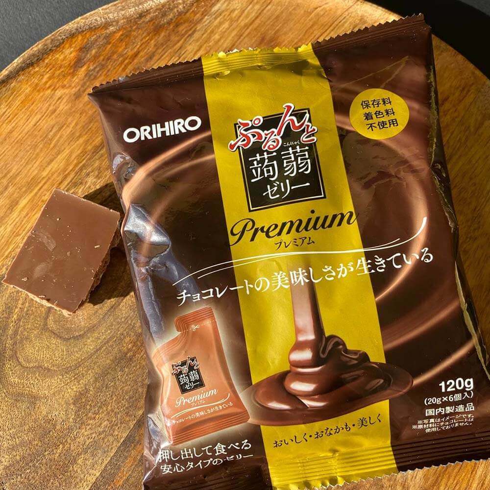 Упаковка ORIHIRO Purunto Konnyaku Jelly Premium Cafe Chocolate на круглом деревянном блюде с кусочком натурального шоколада