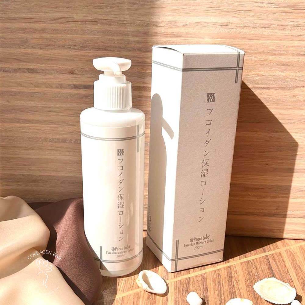 Лосьйон з фукоїданом PEACE LABO Fucoidan Moisture Lotion в об'ємі 200 мл. вертикально на дерев'яному столі з дрібними морськими мушлями