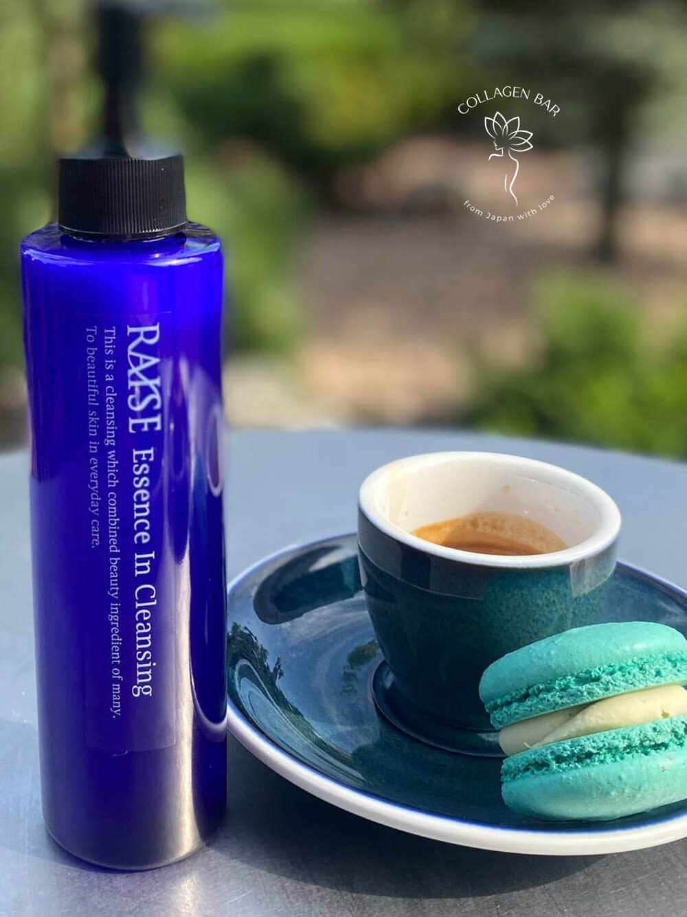 Гель RAISE Essence in Cleansing на столі з чашкою еспресо і макаруном на фоні зеленого літнього саду