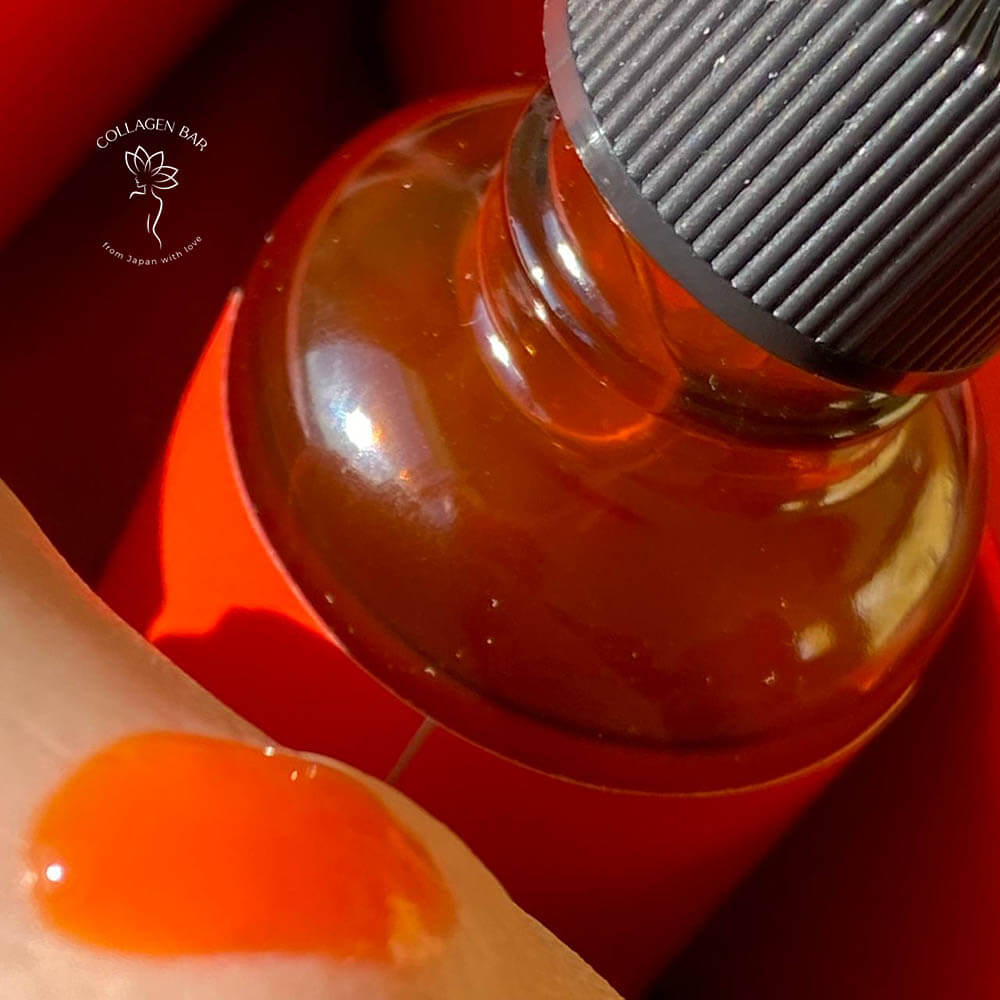 Велика червоно-помаранчева крапля сироватки SALON DE DIAZ Pure AXT Luxury Essence на шкірі. Фото крупним планом.