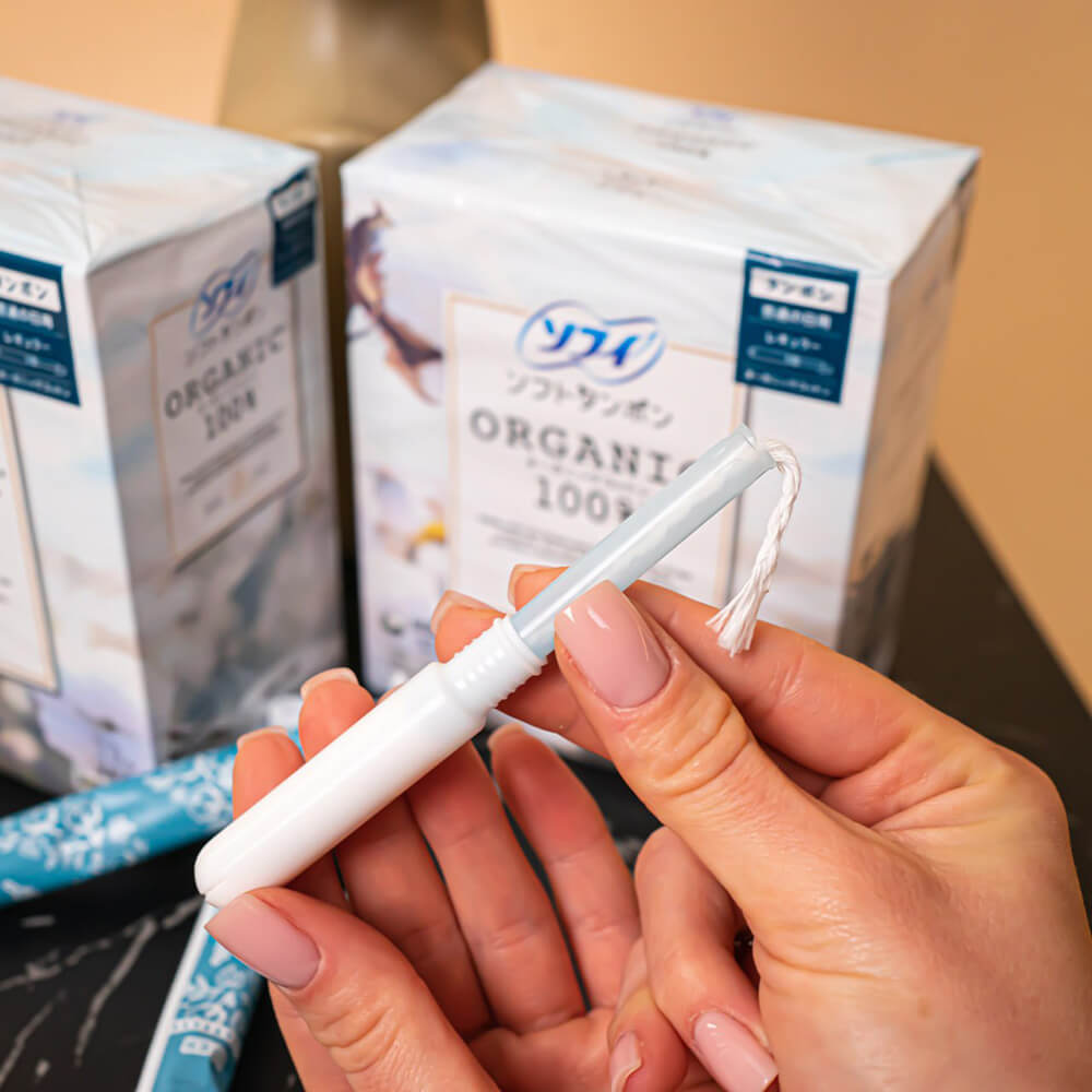 Тампон UNICHARM Sofy Soft Tampon Organic Cotton, витягнутий з індивідуальної упаковки в жіночих руках