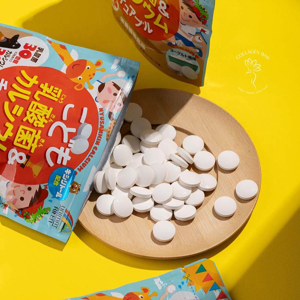 Упаковка Unimat Riken Kids Lactic Bacteria & Calcium і жувальні драже з упаковки в дерев'яній тарілці поруч