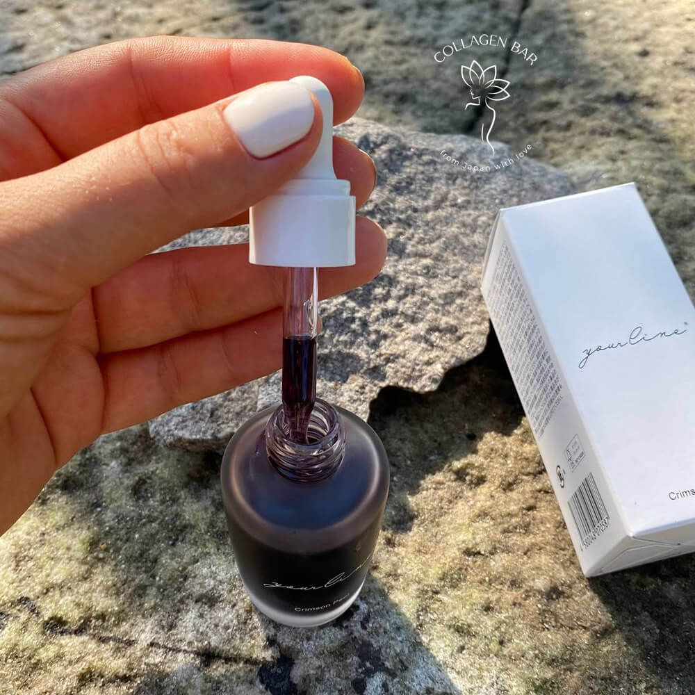 Кришка з піпеткою-дозатором від пілінгу YOURLINE Crimson Peel у жіночій руці з білим манікюром над каменем