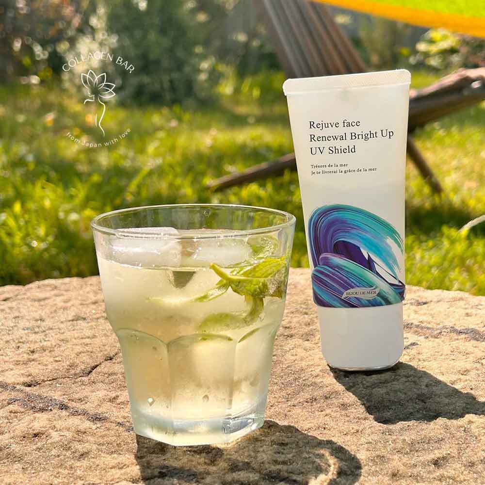Санскрин с HEV-защитой BIJOU DE MER Rejuve face Renewal Bright Up UV Shield зі склянкою води на камені в літньому саду